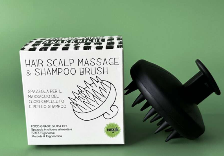 "Spazzola massaggio cuoio capelluto e shampoo in silicone alimentare nera AnARKHIia, con confezione originale su sfondo verde"