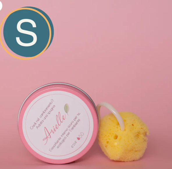 Spugna mestruale Arielle in spugna naturale con anello, accanto al barattolo rosa del prodotto con un mucchio di percarbonato,su sfondo rosa e bollino taglia s