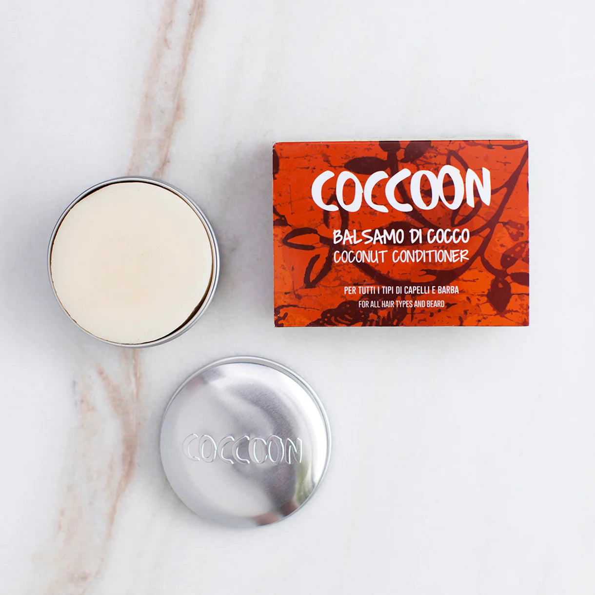 COCCOON: Balsamo Solido di Cocco. colore bianco forma tonda. si vede all'interno del porta solidi coccoon in alluminio. confezione in cartone rossa con scritte bianche