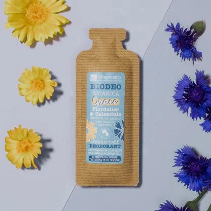 Ricarica deodorante “Biodeo Grace Fiordaliso e Calendula ” di La Saponaria su sfondo azzurro, circondata da fiori di calendula e fiordaliso