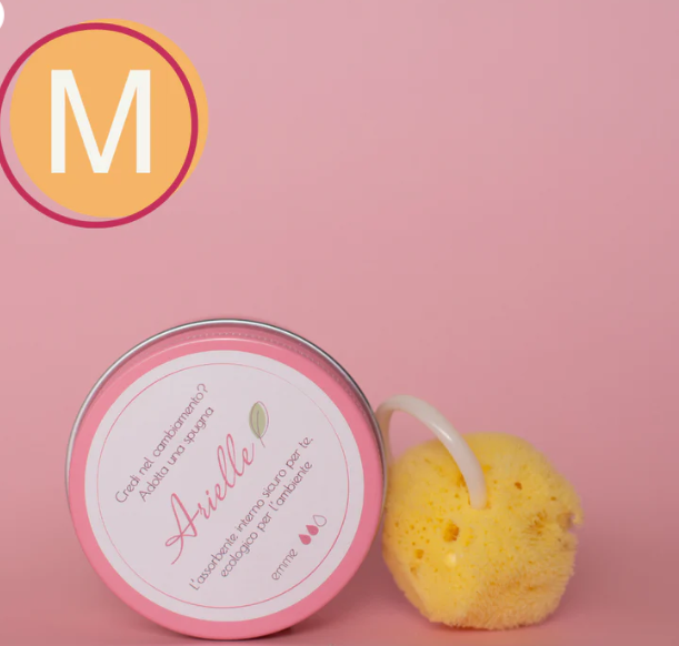 Spugna mestruale Arielle in spugna naturale con anello, accanto al barattolo rosa del prodotto, su sfondo rosa e bollino taglia m
