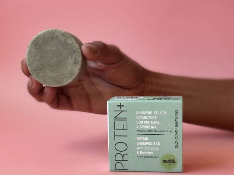 IMMAGINE MANO CHE TIENE SHAMPOO SOLIDO TONDO MARRONE.