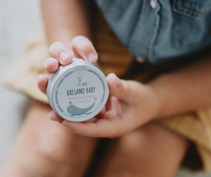 BIMBA CHE TIENE IN MANO BALSAMO IN VASETTO DI LATTA