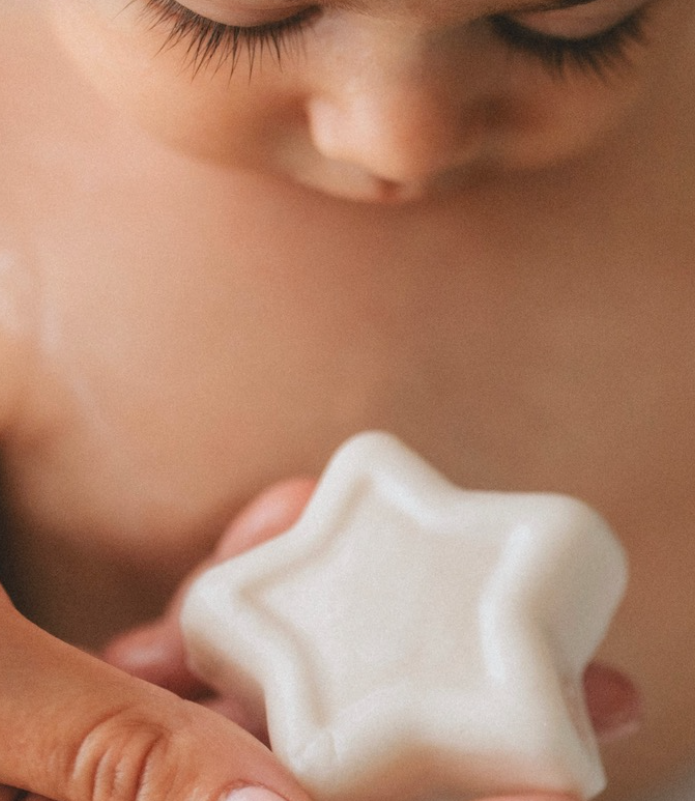 IMMAGINE DI BAMBINO CHE TIENE N MANO UN SAPONE SOLIDO BIANCO A FORMA DI STELLA