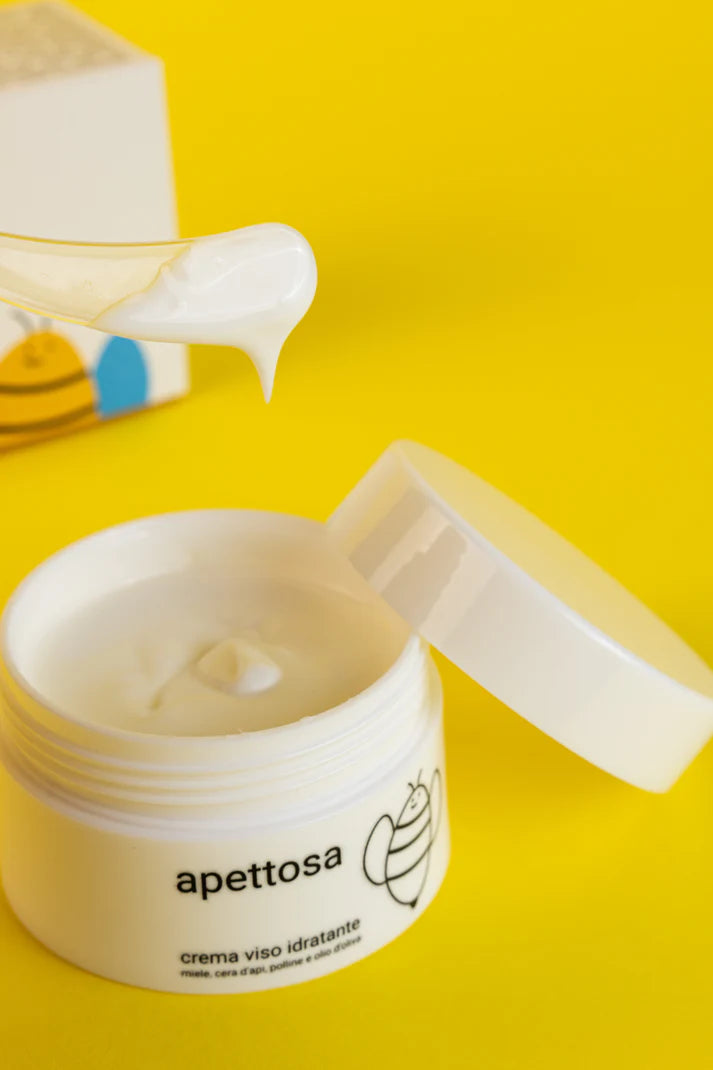 IMMAGINE CREMA VISO IDRATANTE APETTOSA CON BARATTOLO BIANCO APERTO E SPATOLINA CON PARTE DI PRODOTTO SOPRA