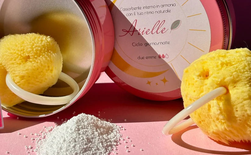 ARIELLE RITMO KIT GIORNO E NOTTE TAGLIA M. SI VEDONO DUE SPUGNE METRUALI CON ANELLO BIANCO, PERCARBONATO IN MUCCHIETTO E SCTOLA ROSA PORTA PRODOTTO IN ALLUMIIO. SFONDO IMMAGINE ROSA