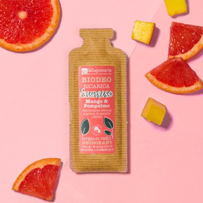 Ricarica deodorante “Biodeo Sunrise Mango & Pompelmo” di La Saponaria su sfondo rosa, circondata da fette di pompelmo e cubetti di mango. 🍊🥭